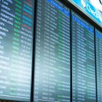 Telas digitais exibem informações e horários de voos em um terminal de aeroporto.