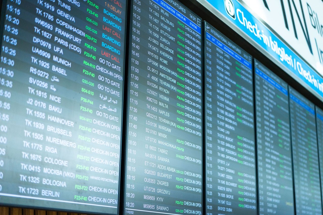Telas digitais exibem informações e horários de voos em um terminal de aeroporto.