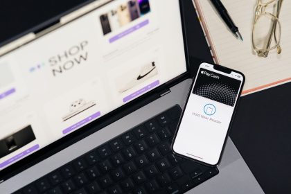 Laptop e smartphone sobre uma mesa, exibindo páginas de compras online e uma interface de pagamento digital.