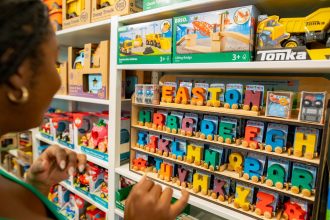 Mulher escolhe brinquedos educativos coloridos em uma loja infantil.