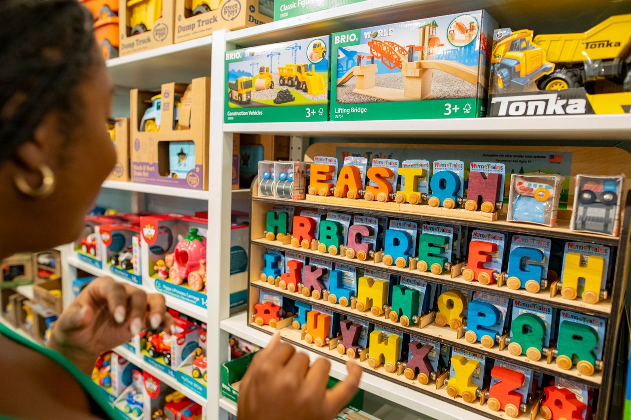 Mulher escolhe brinquedos educativos coloridos em uma loja infantil.