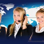 Profissional de atendimento ao cliente usando headset diante de um computador em um call center.