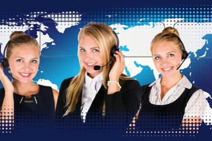 Profissional de atendimento ao cliente usando headset diante de um computador em um call center.